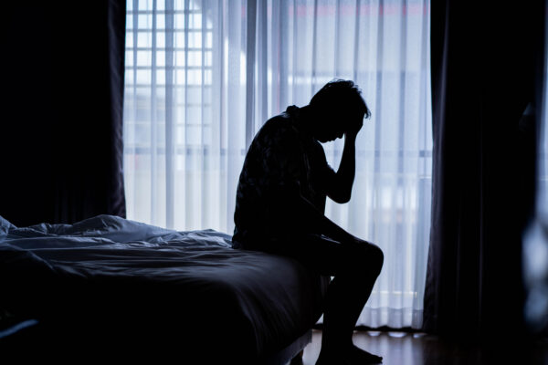Lonely man silhouette sitting on bed, poor sleep, low mood, sleep apnoea, TRT genetics
